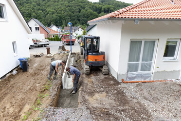 Europa, Deutschland, Rheinland-Pfalz, Männer, die beim Hausbau Ecksteine in den Boden setzen - CSF017690