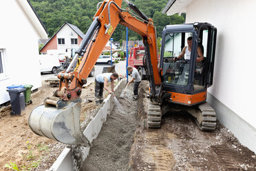 Europa, Deutschland, Rheinland-Pfalz, Männer, die beim Hausbau Ecksteine in den Boden setzen - CSF017692