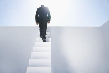 Geschäftsmann im schwarzen Anzug steigt eine Treppe hinauf - PDYF000373