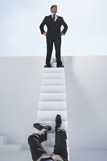 Geschäftsmann steht auf einer Treppe und ein anderer fällt hinunter - PDYF000387