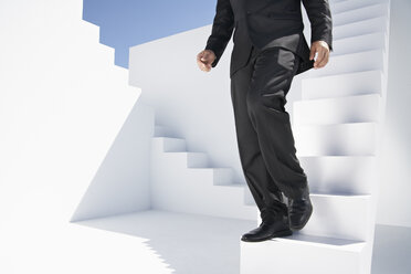 Businessman in black suit moving down stairs - PDYF000405