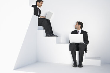 Geschäftsleute sitzen auf einer Treppe und benutzen einen Laptop - PDYF000410