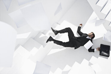 Businessman with briefcase lying down staircase - PDYF000444