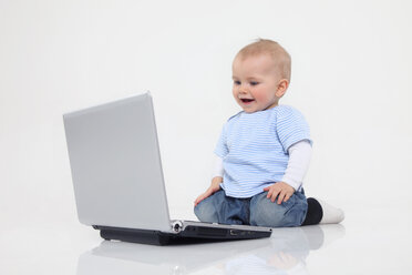 Baby-Junge mit Laptop auf weißem Hintergrund, lächelnd - RDF001076