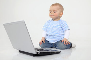 Baby-Junge mit Laptop auf weißem Hintergrund, lächelnd - RDF001077