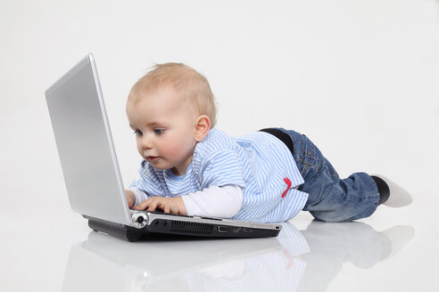Baby-Junge mit Laptop auf weißem Hintergrund, lächelnd - RDF001079