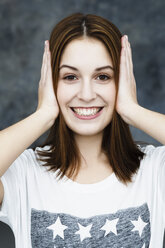 Porträt einer jungen Frau, die sich die Ohren zuhält, lächelnd - SPOF000062