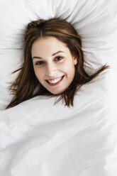 Porträt einer jungen Frau auf dem Bett liegend, lächelnd - SPOF000070