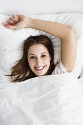 Porträt einer jungen Frau auf dem Bett liegend, lächelnd - SPOF000071