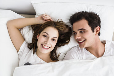 Young couple lying on bed, smiling - SPOF000072