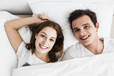 Junges Paar auf dem Bett liegend, lächelnd - SPOF000073