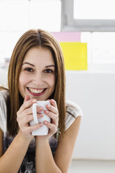 Porträt einer jungen Frau, die lächelnd eine Tasse hält - SPOF000088