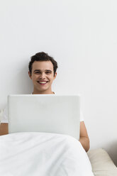 Portrait of young man using laptop, smiling - SPOF000096