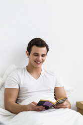 Junger Mann liest Buch, lächelnd - SPOF000105