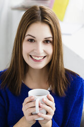 Portrait of young woman holding mug, smiling - SPOF000109