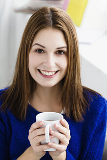 Porträt einer jungen Frau, die lächelnd eine Tasse hält - SPOF000109