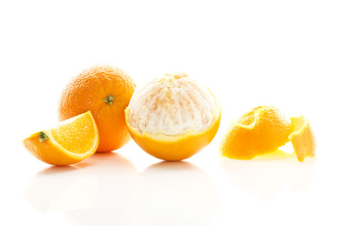 Geschälte und ganze Orangen auf weißem Hintergrund, Nahaufnahme, lizenzfreies Stockfoto