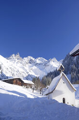 Deutschland, Bayern, Blick auf kleine Kapelle in Dorf mit schneebedeckten Bergen im Hintergrund - ALE000009