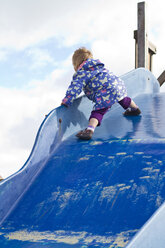 Germany, Girl playing on blue slide, smiling - JFEF000068