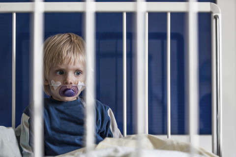 Österreich, Wels, Junge sitzt auf Krankenhausbett, lizenzfreies Stockfoto