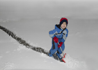 Österreich, Junge beim Schneeräumen mit Schneeschaufel - CWF000017