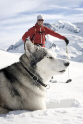 Österreich, Mann beim Skifahren mit Lawinenhund im Schnee - RN001183