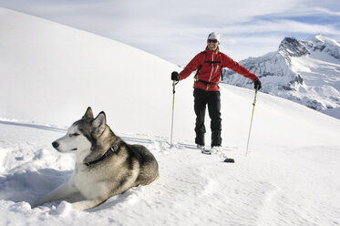 Austria, Man skiing with Avalanche Dog in snow - RN001188