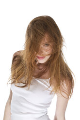 Junge Frau mit vom Wind zerzausten Haaren vor weißem Hintergrund, Nahaufnahme - MAEF006135