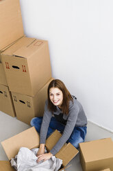 Germany, Munich, Portrait of young woman packing cardboard box, smiling - SPOF000235