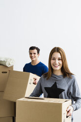 Germany, Munich, Young couple holding cardboard box, smiling - SPOF000240