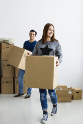 Germany, Munich, Young couple holding cardboard box, smiling - SPOF000242