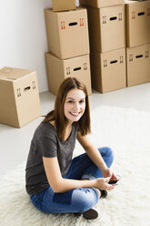 Germany, Munich, Portrait of young woman using mobile phone, smiling - SPOF000244