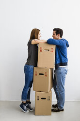 Germany, Munich, Young couple leaning on cardboard boxes, smiling - SPOF000246