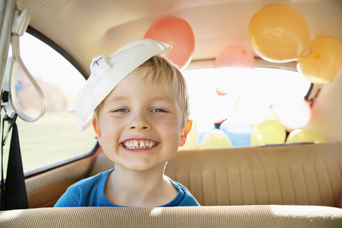 Deutschland, Nordrhein-Westfalen, Köln, Porträt eines Jungen im Auto mit Osterhasenmaske, lächelnd - PD000319