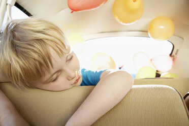 Germany, North Rhine Westphalia, Cologne, Tired boy leaning on car seat - PD000327