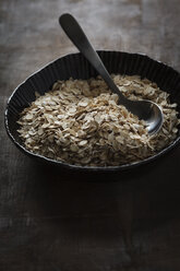 Bowl of oat flakes with spoon on table, close up - EVG000079