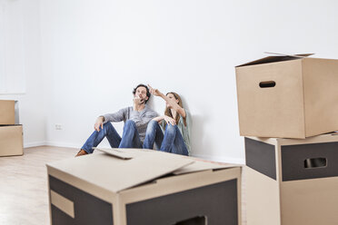 Couple sitting on floor with moving boxes - FMKF000560