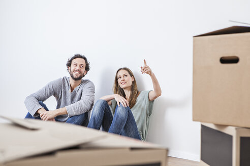 Couple sitting on floor with moving boxes - FMKF000561