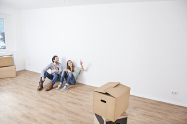 Couple sitting on floor and pointing at wall - FMKF000710