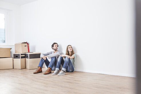 Couple sitting on floor, looking away - FMKF000563