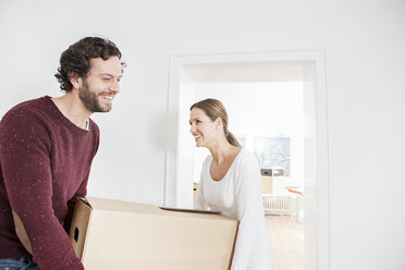 Lächelndes Ehepaar beim Ausladen der Kisten in ihrem neuen Haus - FMKF000576