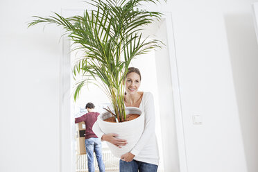 Woman unloading potted plant while man standing in background - FMKF000578
