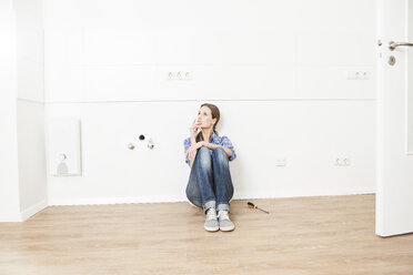 Woman sitting on floor, looking away - FMKF000603