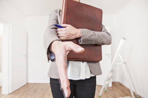 Woman with file and pen approaching for shake hand - FMKF000641