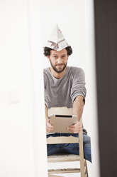 Portrait of man sitting on chair and holding digital tablet, smiling - FMKF000588