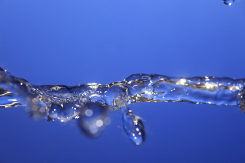 Splashing water against blue background - JTF000307