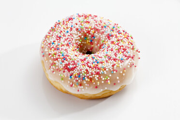Doughnut mit Zuckerguss und Streuseln auf weißem Hintergrund, Nahaufnahme - CSF017864