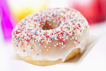 Doughnut topped with icing and sprinkles, close up - CSF017900