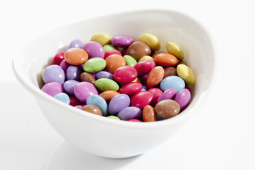 Bowl of chocolate buttons on white background, close up - CSF017992