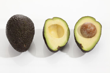 Whole and halved avocado ripe on white background, close up - CSF017972
